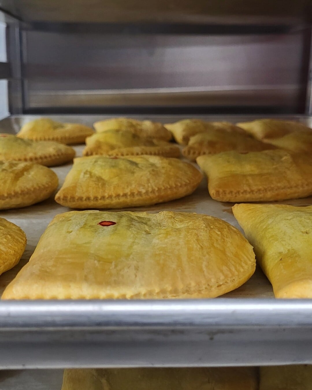 A wide row of freshly baked Randy's patties on a parchment-lined tray