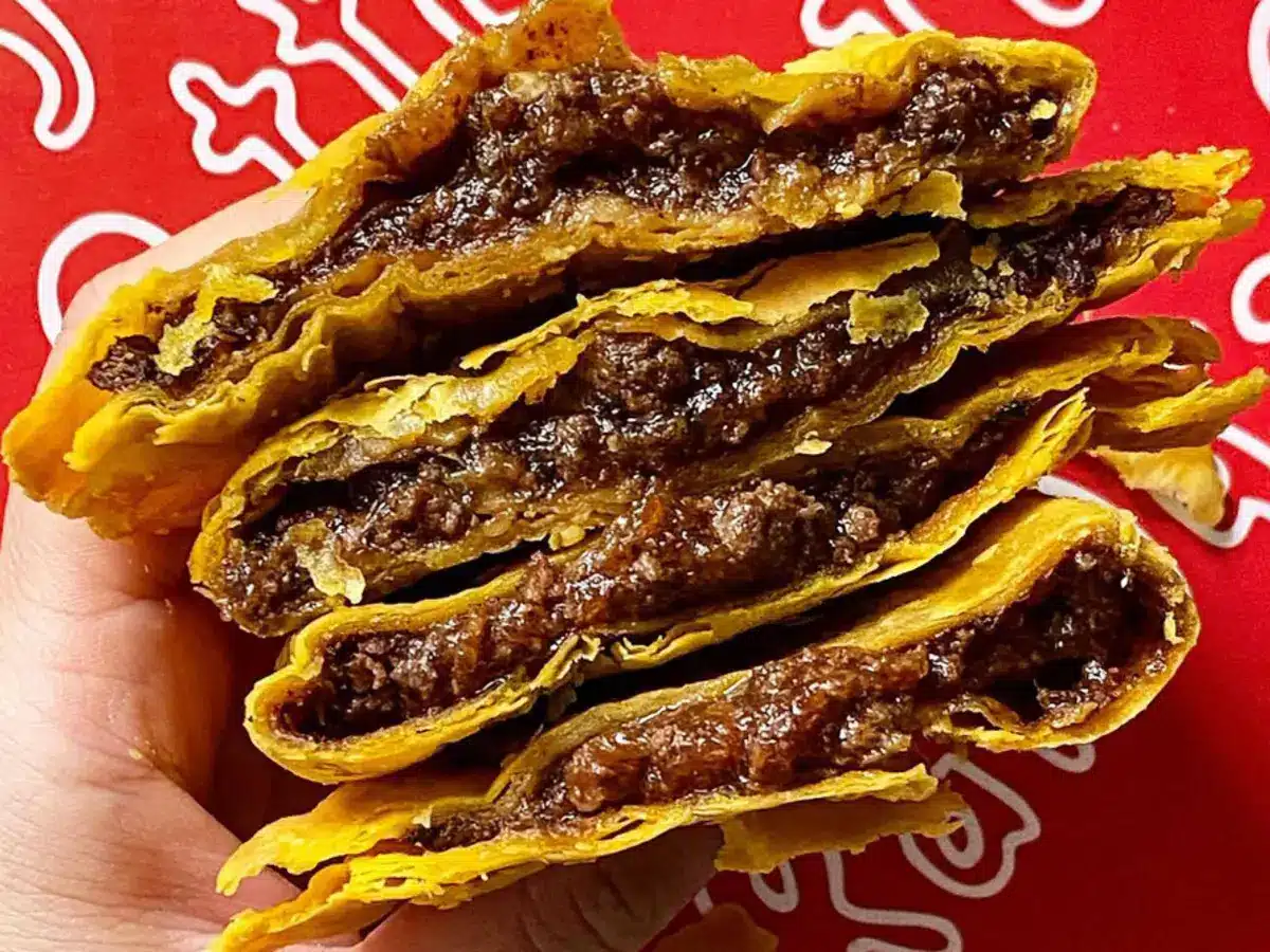 A Randy's beef patty sliced open, showing the seasoned filling inside a flaky golden crust